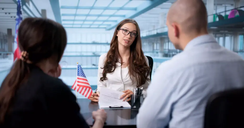 An immigration lawyer reviews legal documents during a consultation with a couple, featuring a professional office background.