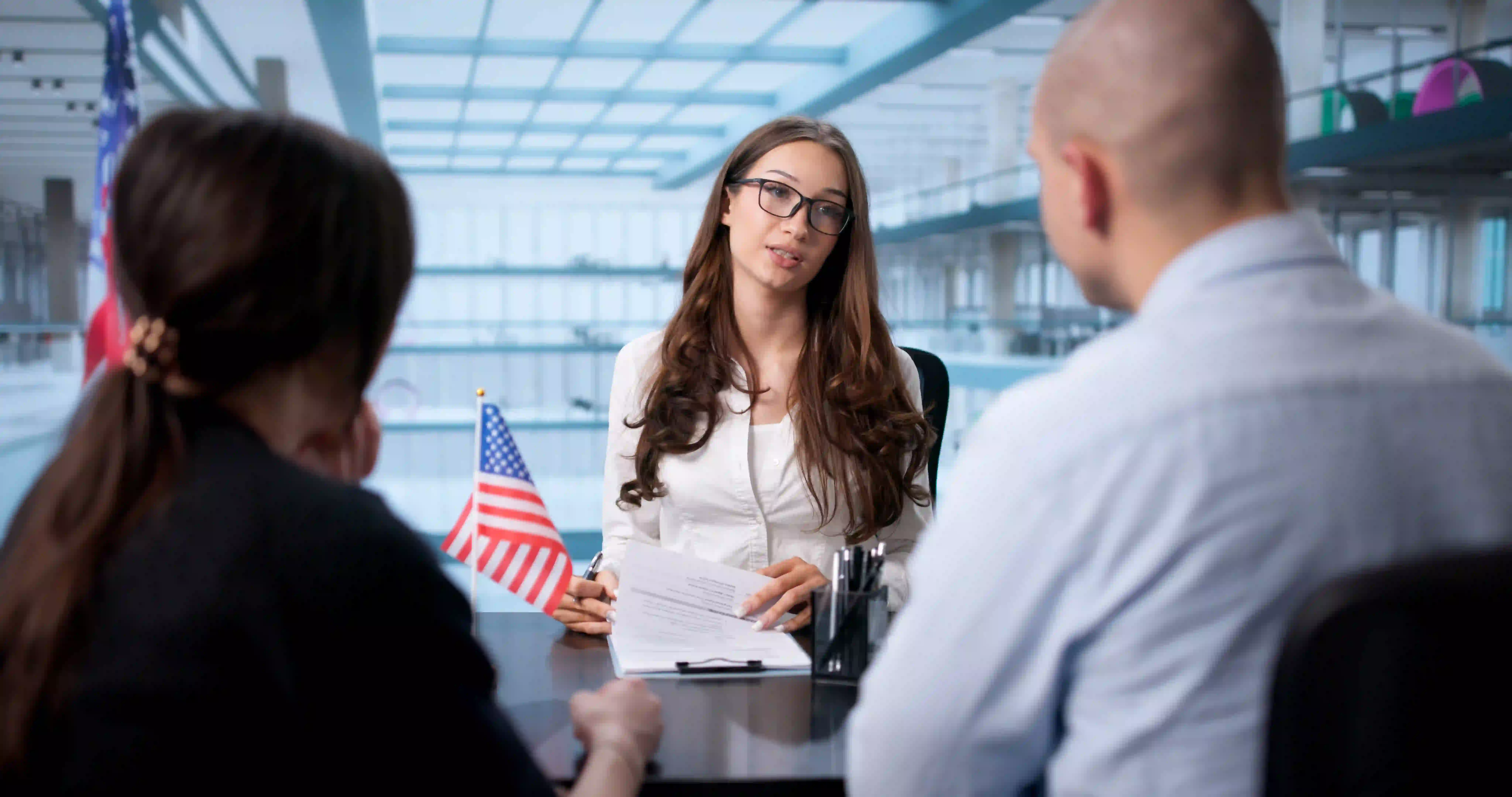 An immigration lawyer reviews legal documents during a consultation with a couple, featuring a professional office background.