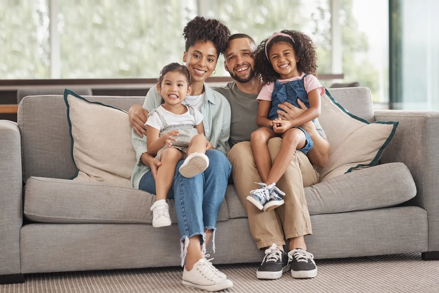 Happy family sitting on a couch, representing E-2 visa family members moving together.
